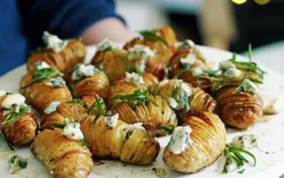A group of baked Hasselback Potatoes with Gorgonzola and Honey on a white serving tray