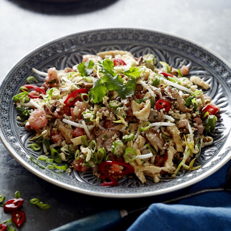 A patterned blue bowl of vegan cauliflower fried rice with parsley adorned on top