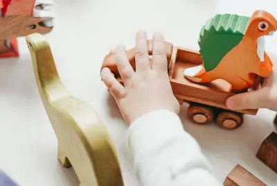 Young child playing with wooden dinosaur toys